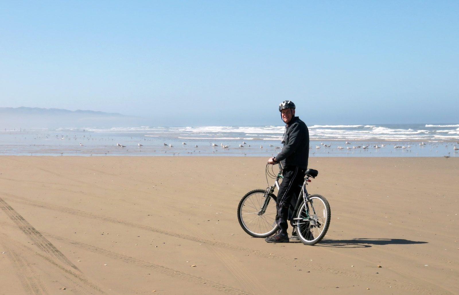 starszy pan z rowerem na plaży
