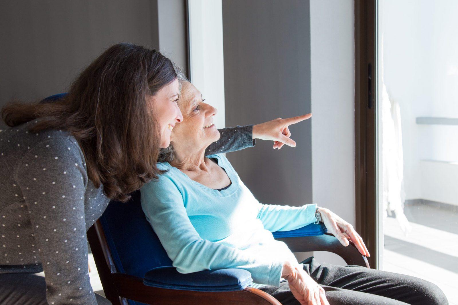 Obrazek przedstawiający kobietę i starszą panią siedzącą na wózku inwalidzkim.